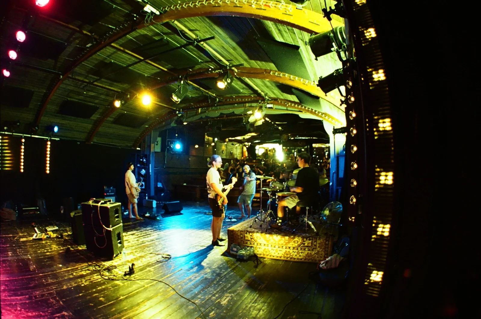 Hannetones from behind the guitarist: drummer and bassist on the arched wooden stage